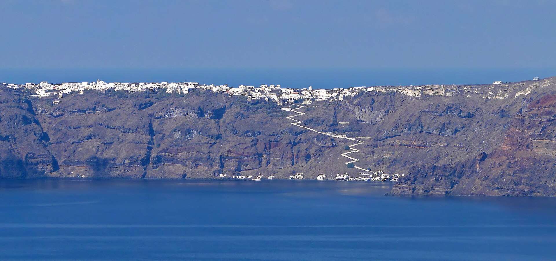 Manolas on Thirassia's caldera rim, with the stair path to the sea